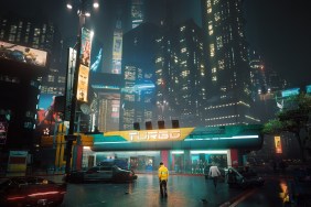 Cyberpunk 2077: a person in a yellow jacket looks insignificant against the neon buildings of Night City.